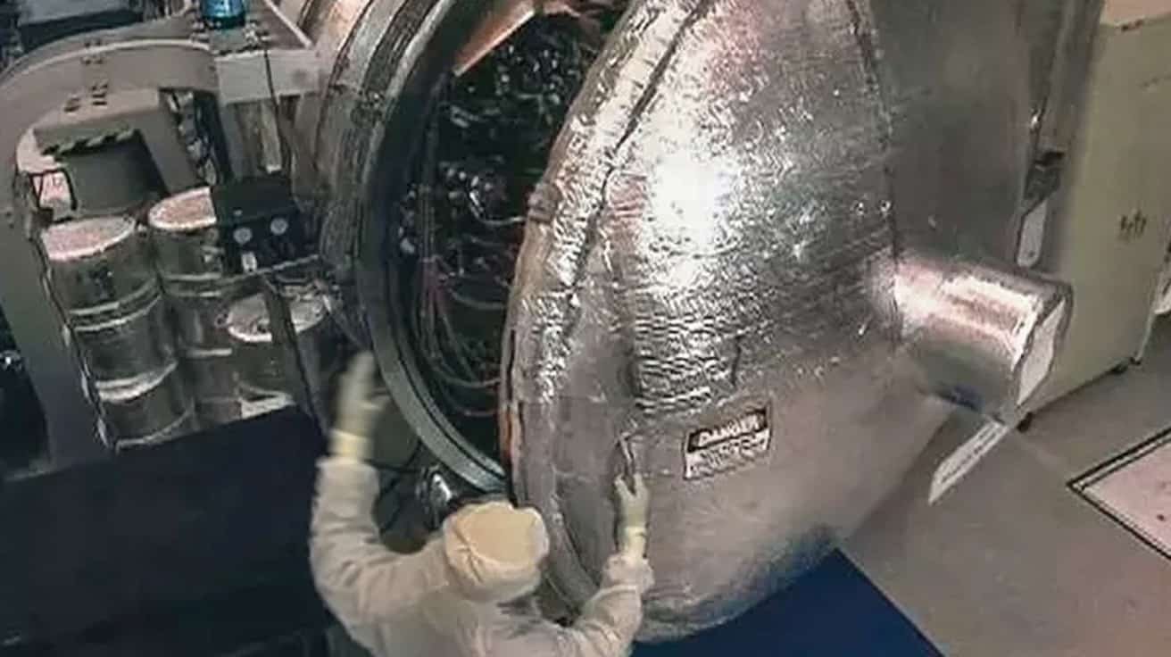 A technician carefully assembling a complex, lightweight aluminum vacuum chamber in a clean lab environment