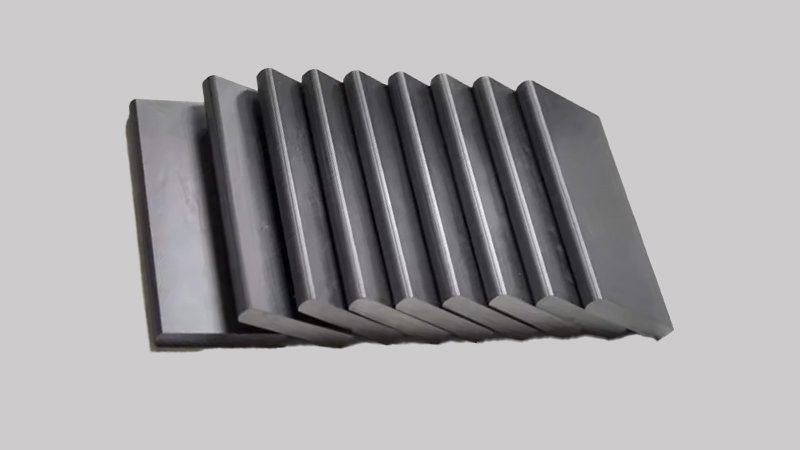 A macro photograph showing the unique texture of a dark gray, self-lubricating carbon-graphite vane