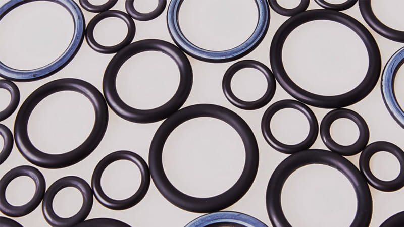 A collection of different colored and sized rubber O-rings laid out neatly on a clean, white surface.