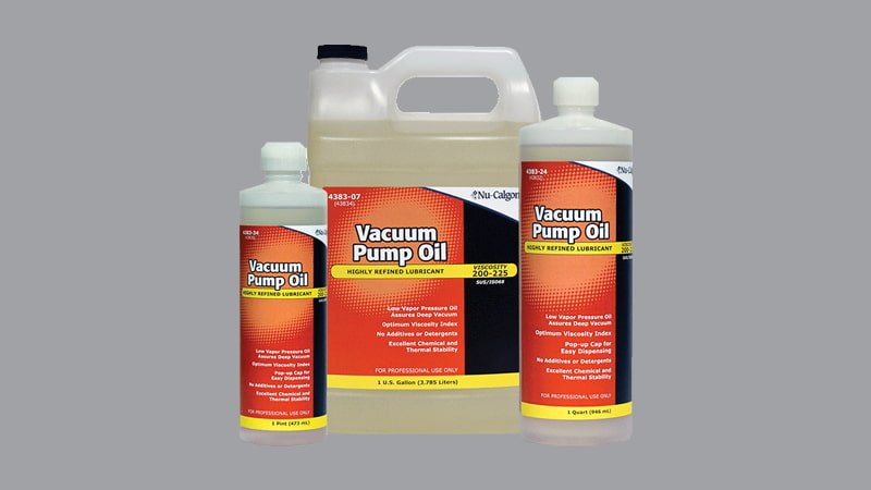 A technician holding two different bottles of vacuum pump oil, looking at the labels with a confused expression