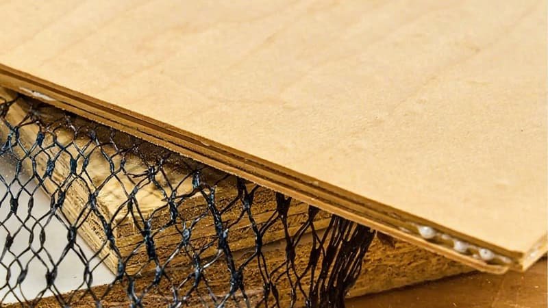 A woodworker wearing safety glasses is using a band saw to carefully re-saw a thick piece of walnut into thin, flexible strips for lamination