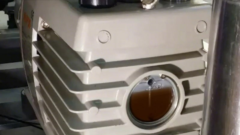 A composite image showing three vacuum pump sight glasses side-by-side: one with milky oil, one with dark black oil, and one with foaming oil