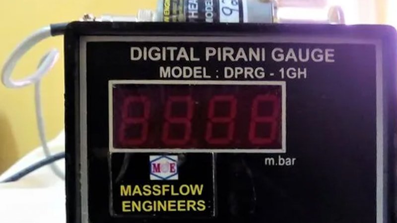 A toolkit layout for industrial testing: a professional digital vacuum gauge, a new gallon of synthetic vacuum pump oil, and a set of stainless steel KF flange fittings