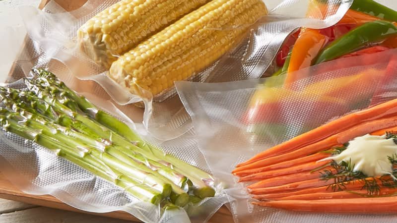 Person carefully placing a food item into a vacuum sealer bag, leaving adequate headspace