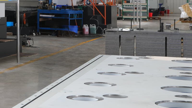 A workbench with small blocks of polished stainless steel, matte aluminum, and clear acrylic side-by-side