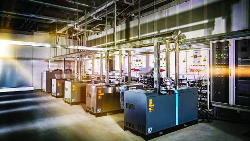 A vacuum pump operating in a hot, industrial environment, with heat haze shimmering above it