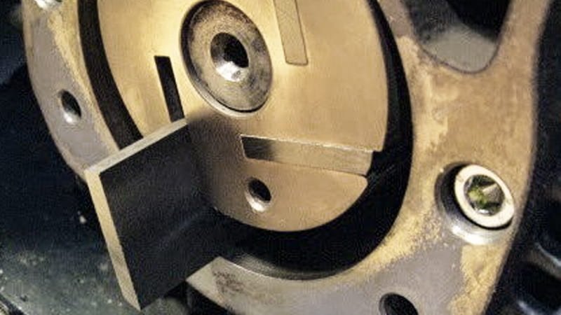 A technician wearing gloves holding a new vane next to a visibly worn-down vane, showing the material that has been consumed